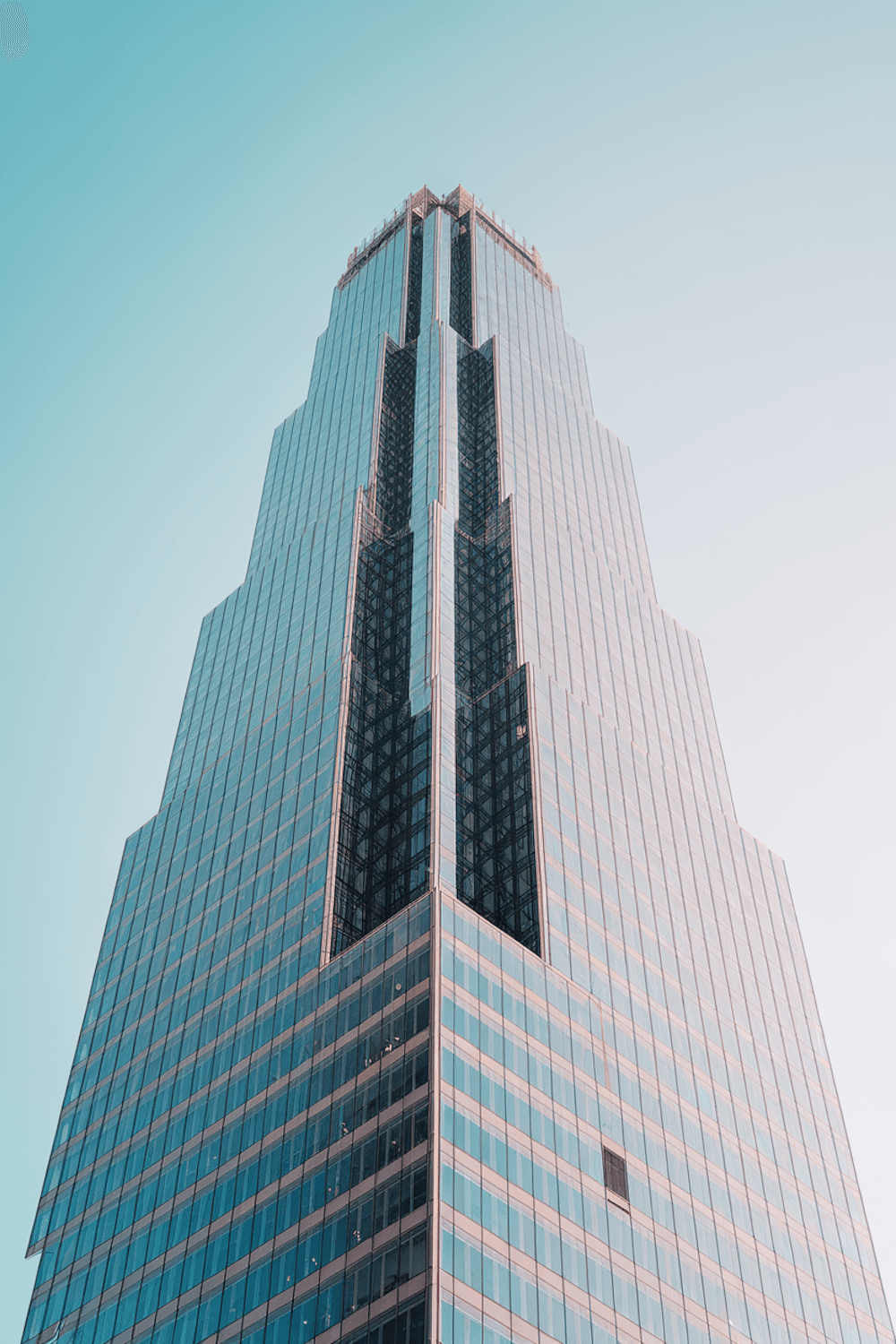 Glass office tower reflecting a blue sky