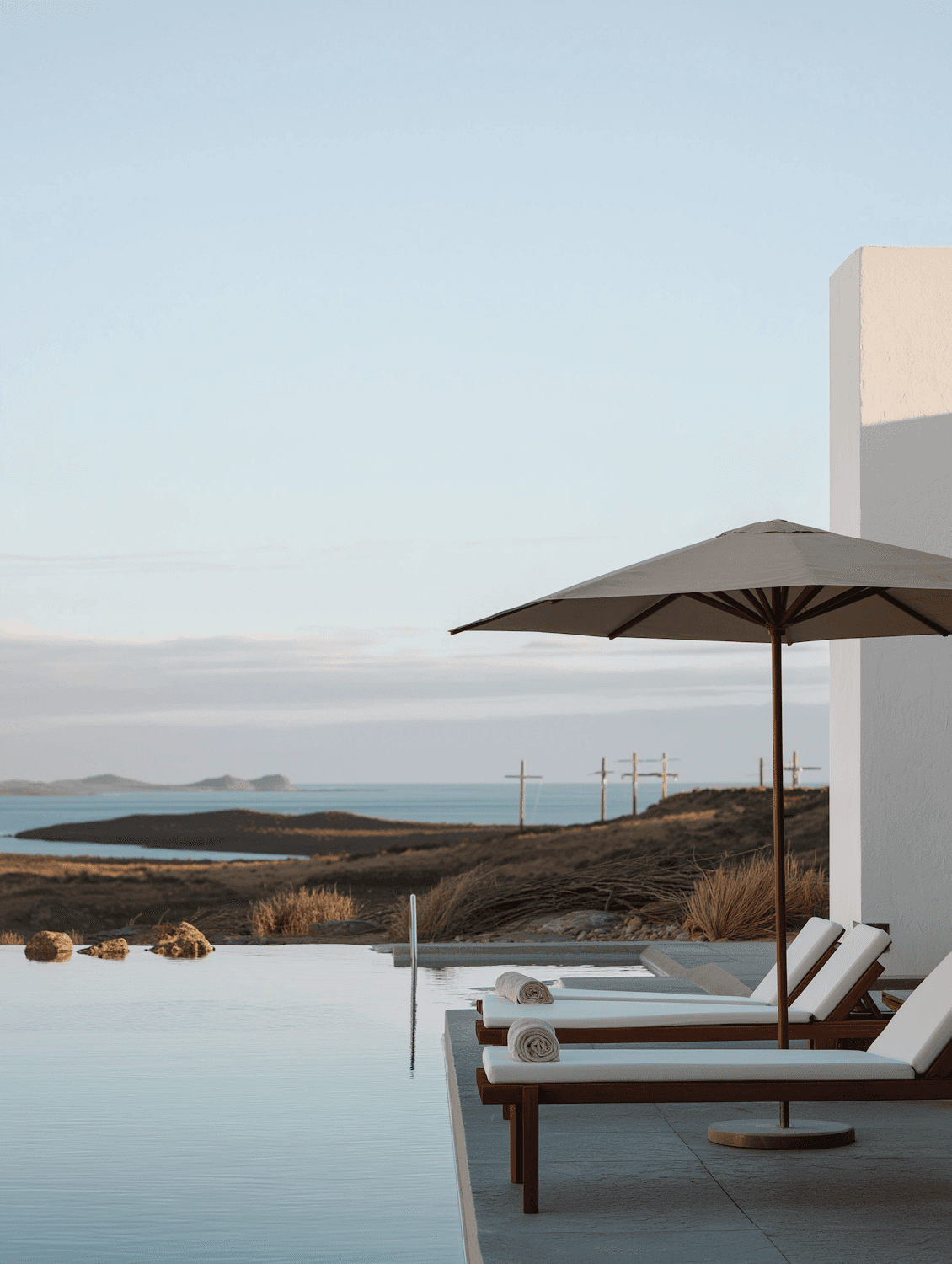Infinity pool with timber loungers under a soft blue sky